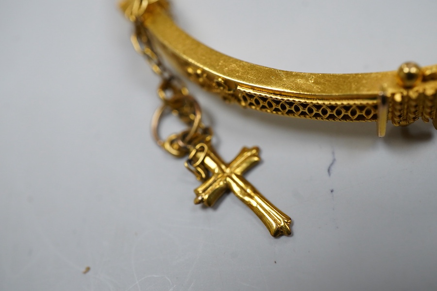Two Victorian gold bangles, late 19th century, each of hinged design, with rope twist decoration, one later set with a carré-cut diamond, the other suspending a cross from a safety chain, inner circumferences approximate
